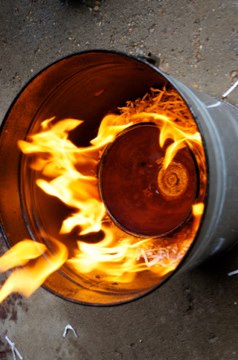 a red hot piece of ceramics surrounded by combustible materials undergoing reduction in a barrel, example of Raku firing method.