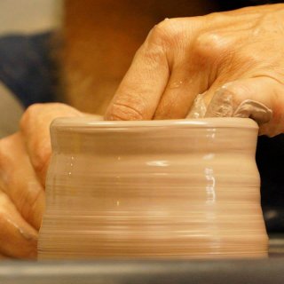 hands throwing clay on a potter's wheel
